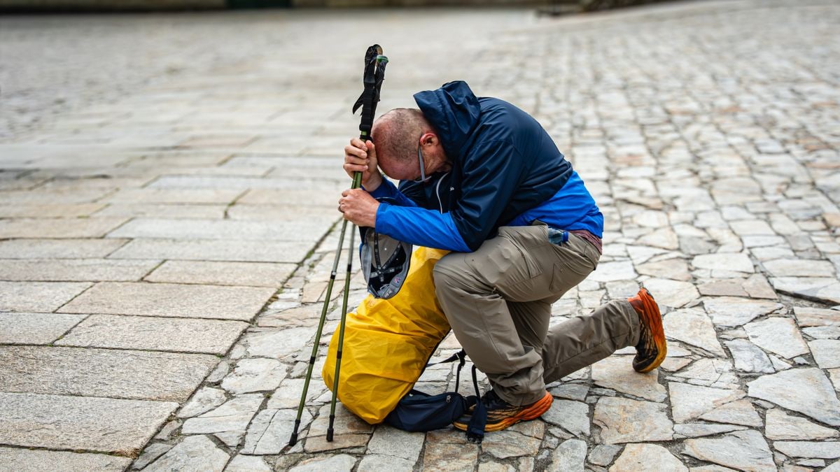 A traveler rests on cobblestones, symbolizing a pilgrimage's completion.